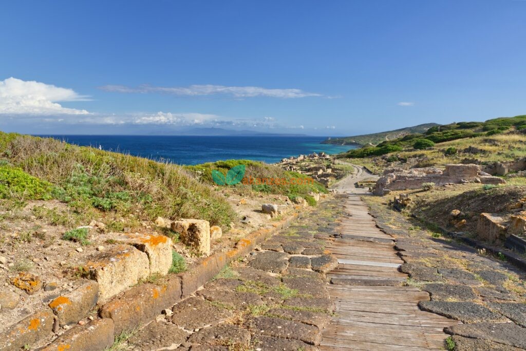 Ancient ruins sit near the bright blue ocean.